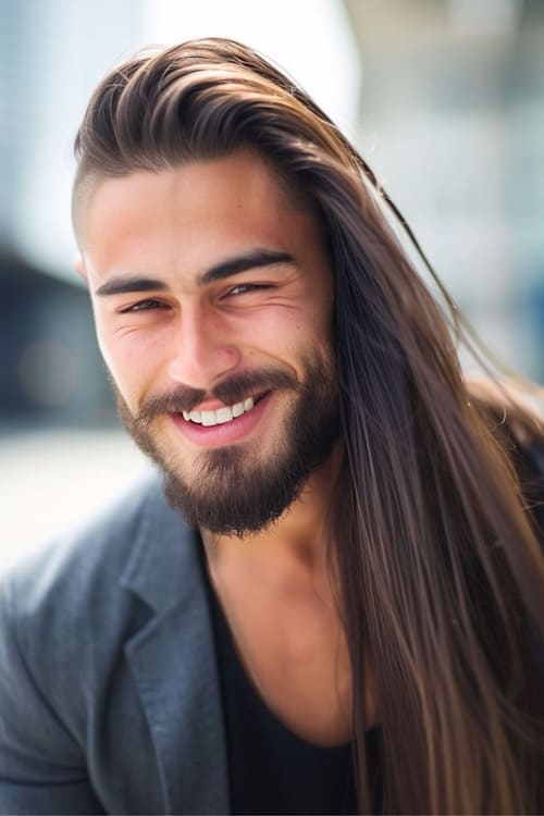 Penteado longo de corte assimétrico em homem atraente com barba.