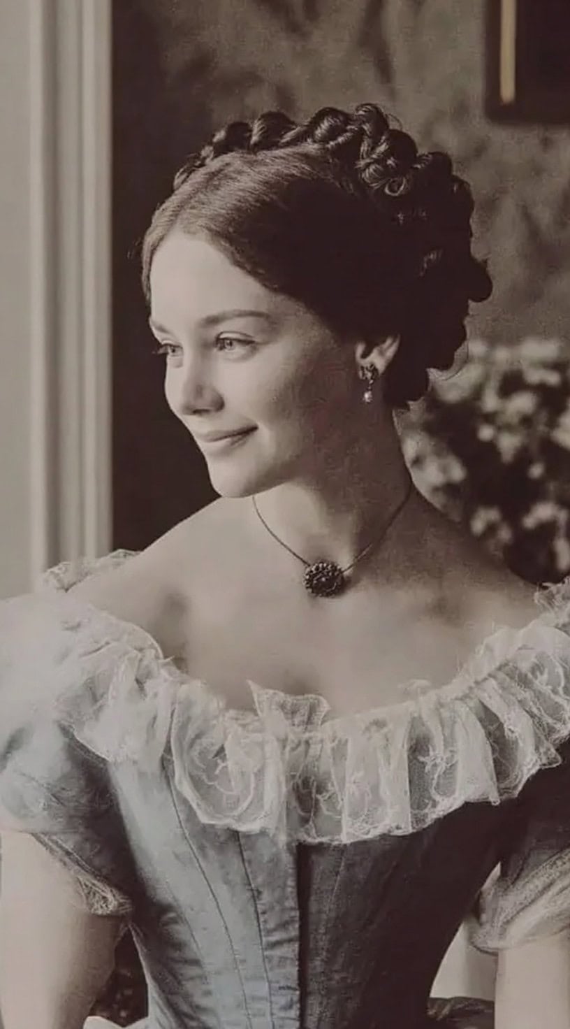 Jovem com cabelos escuros estilizados em uma coroa de cachos definidos ao redor da cabeça.