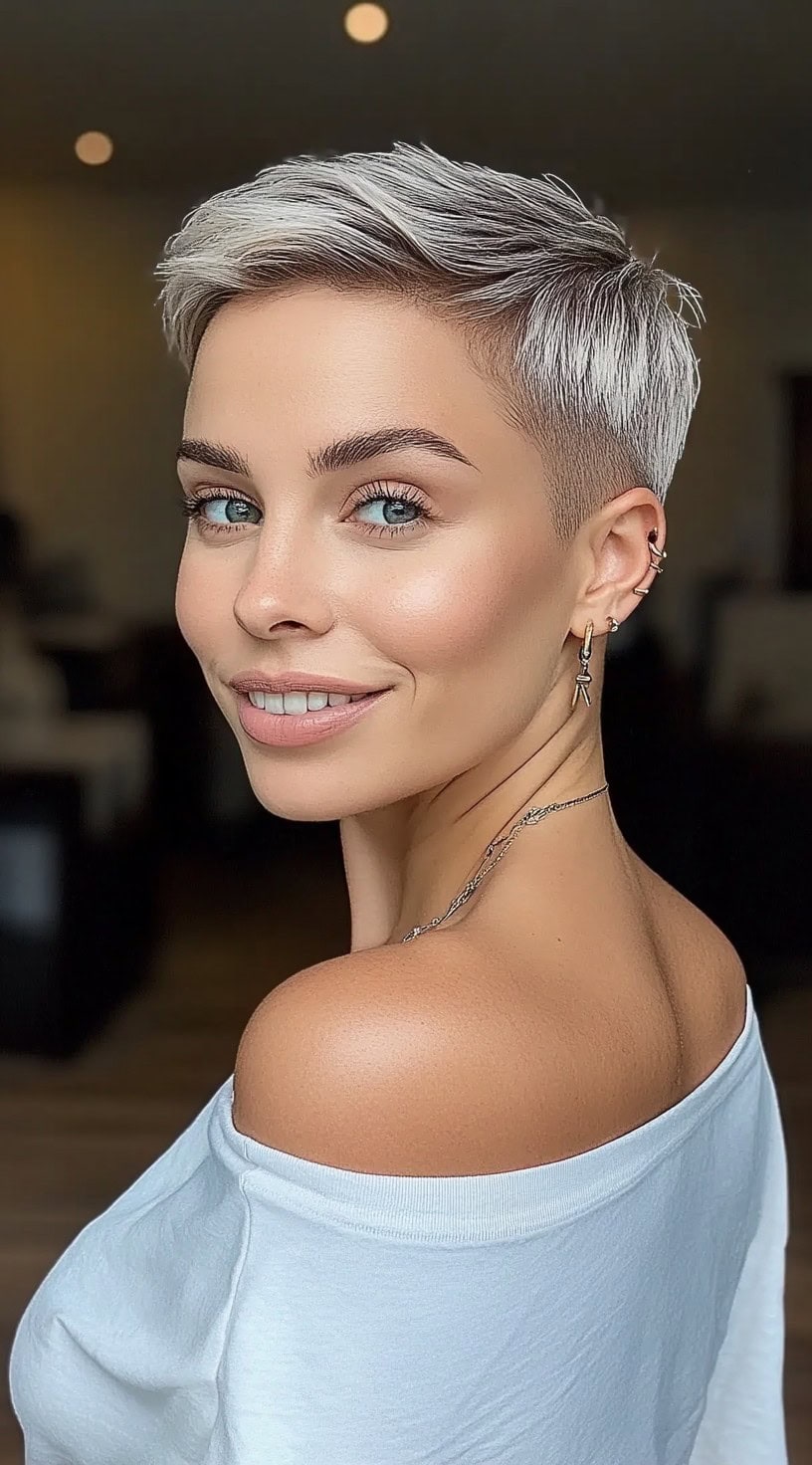 Uma mulher com uma pixie de prata gelada, com volume na coroa e lados cônicos, sorrindo por cima do ombro.