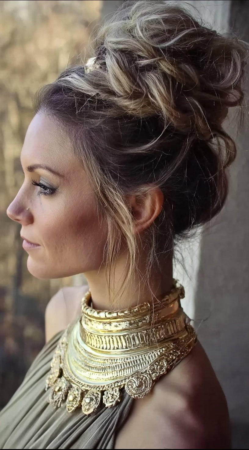 Vista lateral de uma mulher com um penteado suavemente texturizado, com seções torcidas e fios soltos emoldurando o rosto.